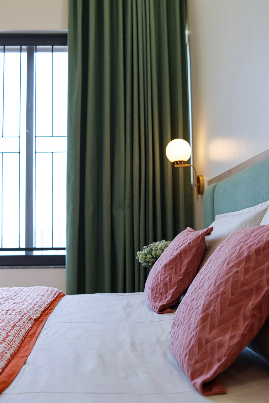a bed with pink pillows and a lamp next to a window