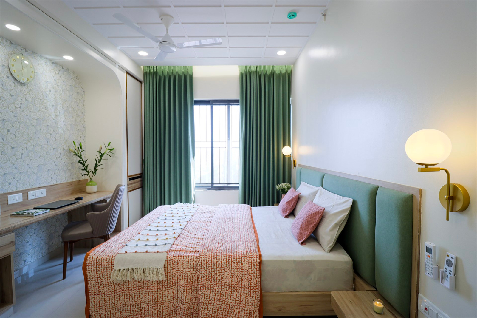 a bed with green curtains and a desk